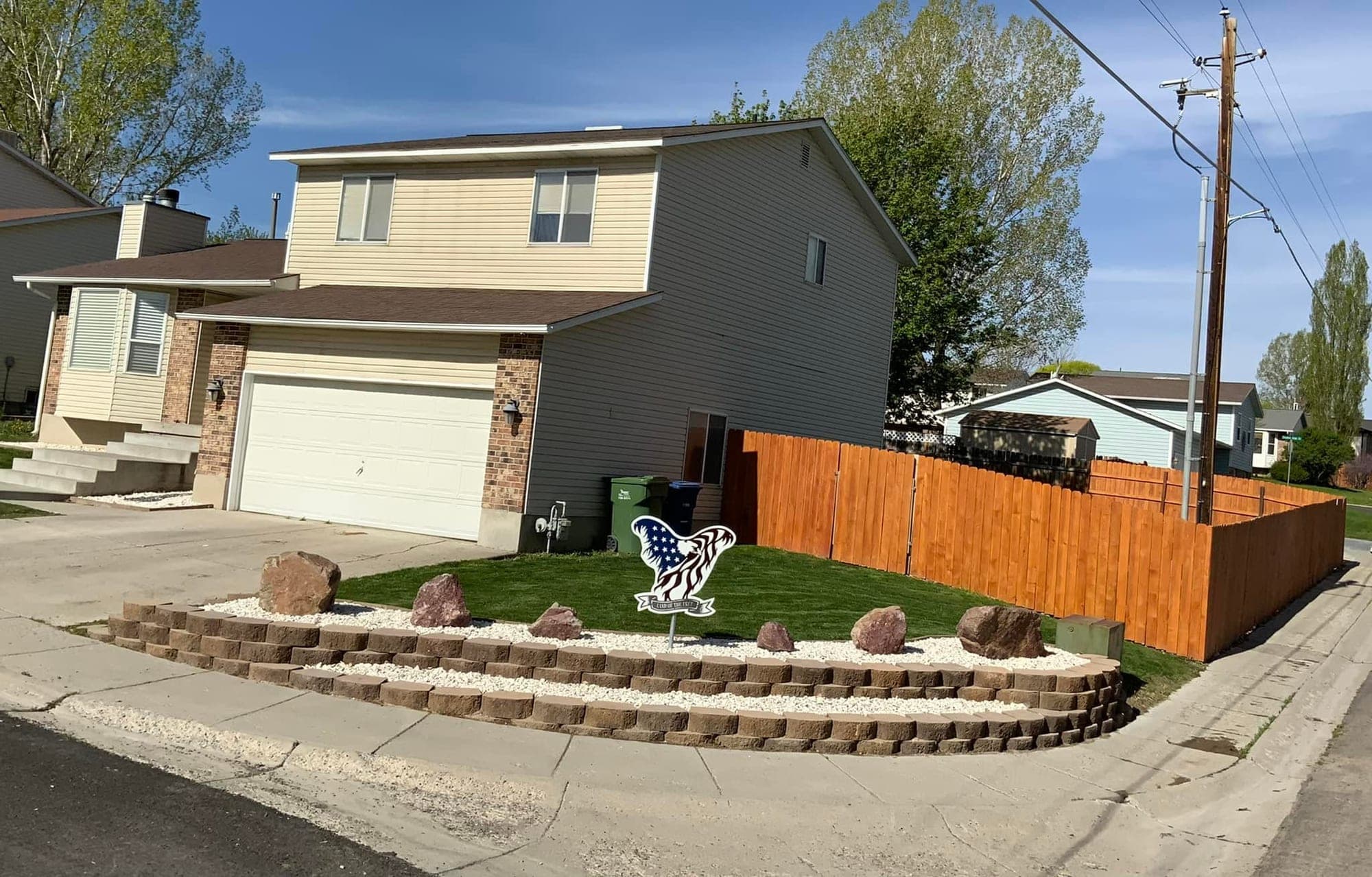 Front yard with a curved block retaining wall, white rock, boulders, new sod and a cedar dog-ear fence, Elko, Nevada