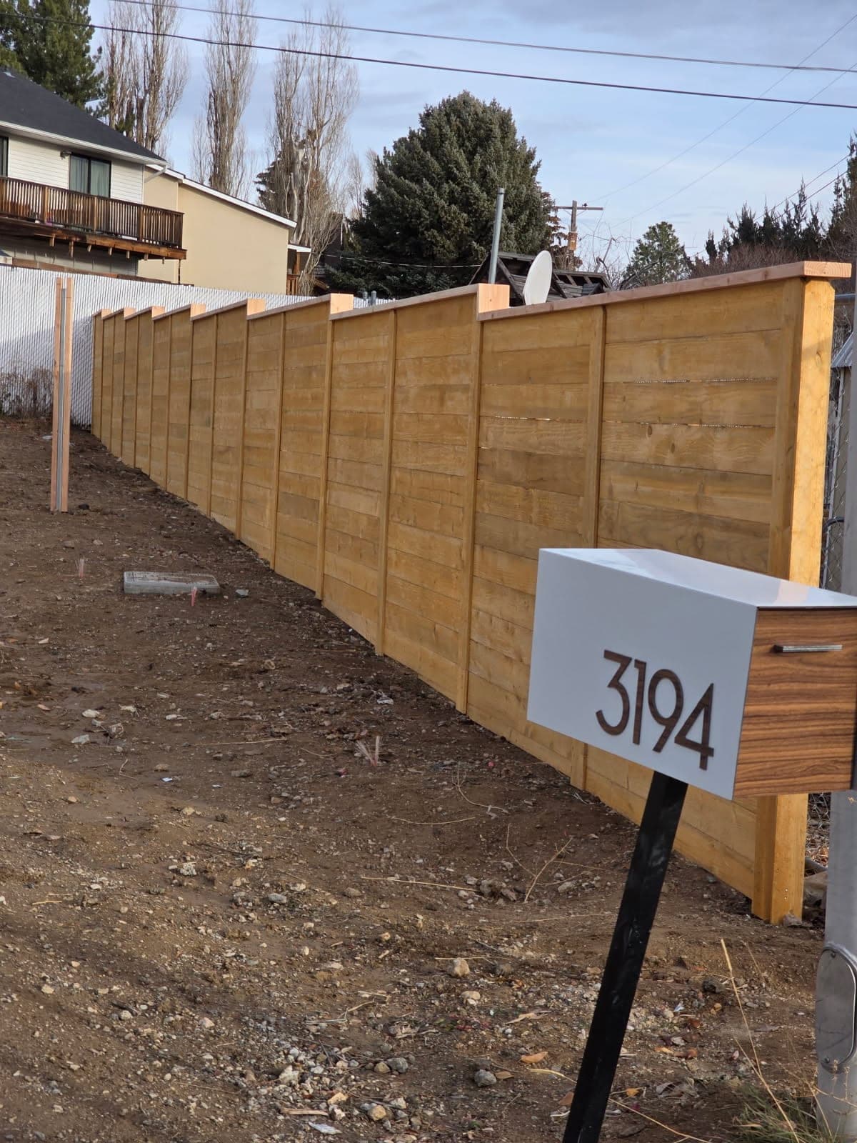 Horizontal cedar privacy fence with a cap rail and a modern white mailbox in front, Elko, Nevada
