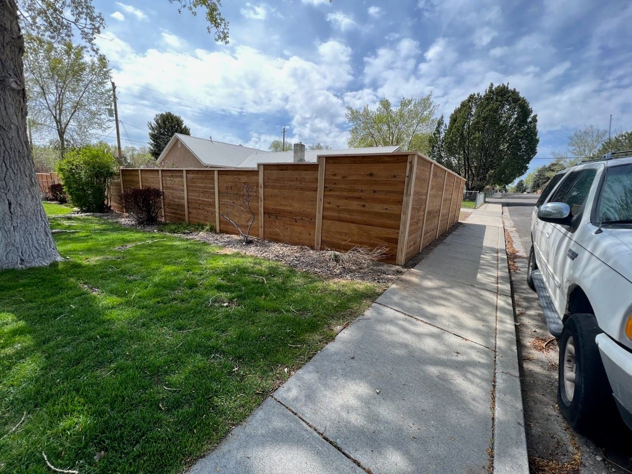 Horizontal cedar privacy fence along a residential sidewalk with lawn and shrubs, Elko, Nevada