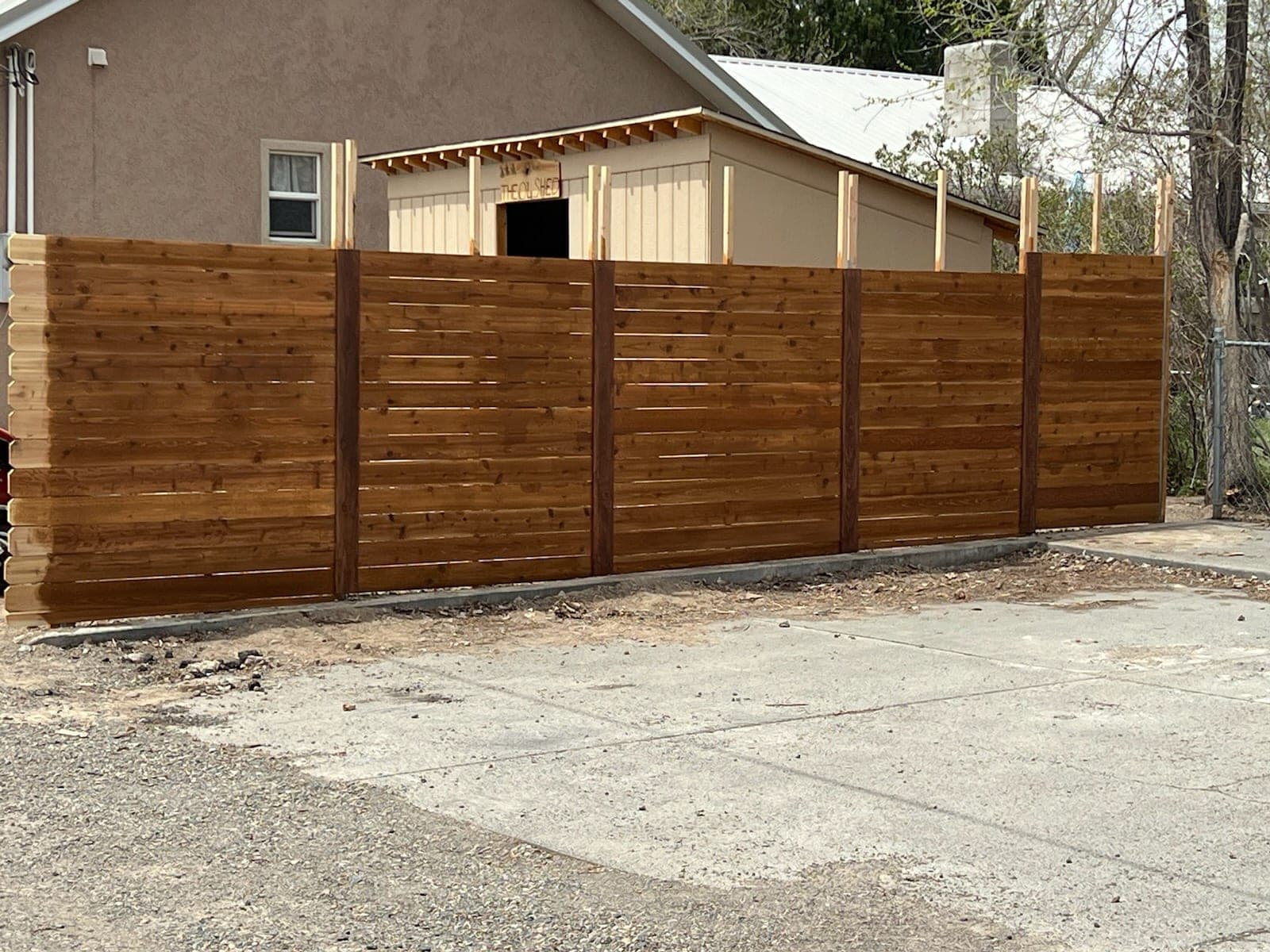 Stained horizontal cedar privacy fence with dark posts next to a driveway in Elko, Nevada
