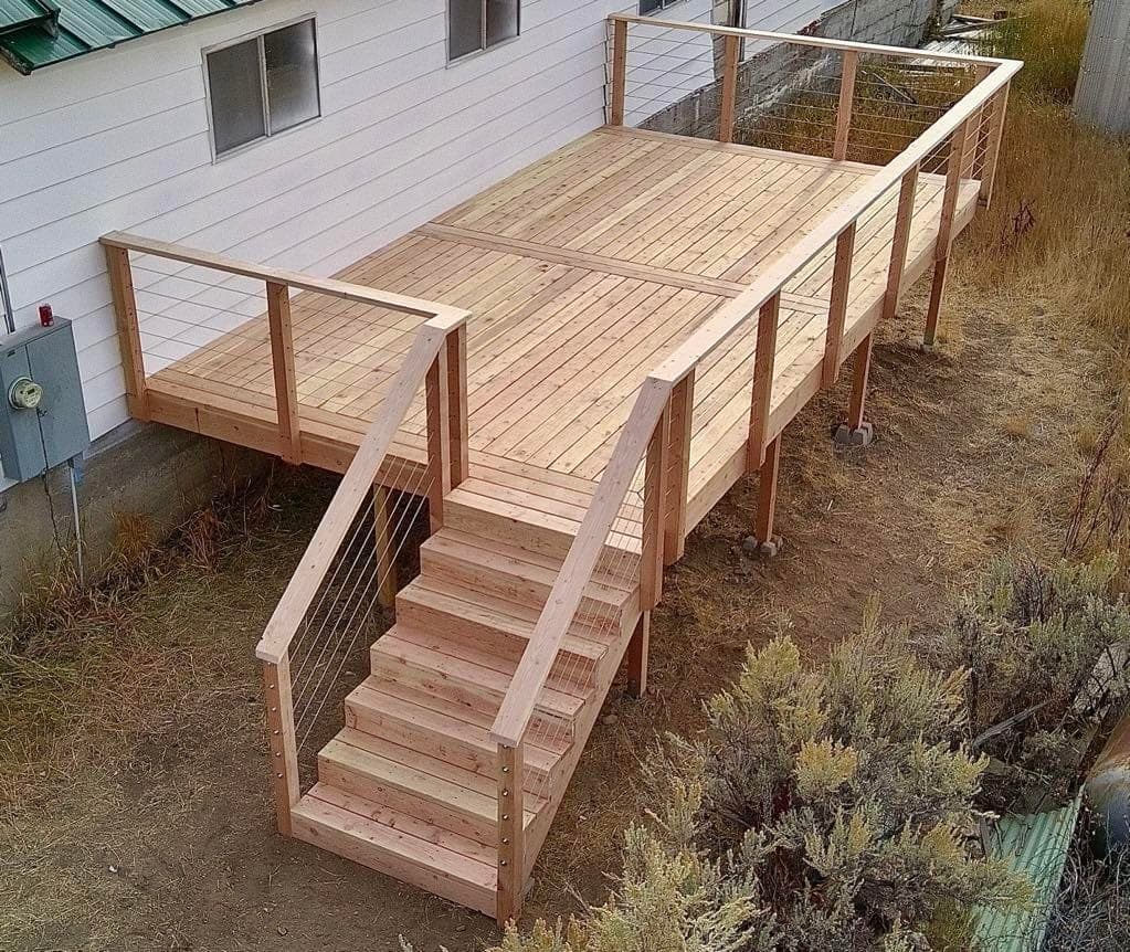 Overhead view of a new cedar deck with cable railing and stairs beside a white house, Elko, Nevada