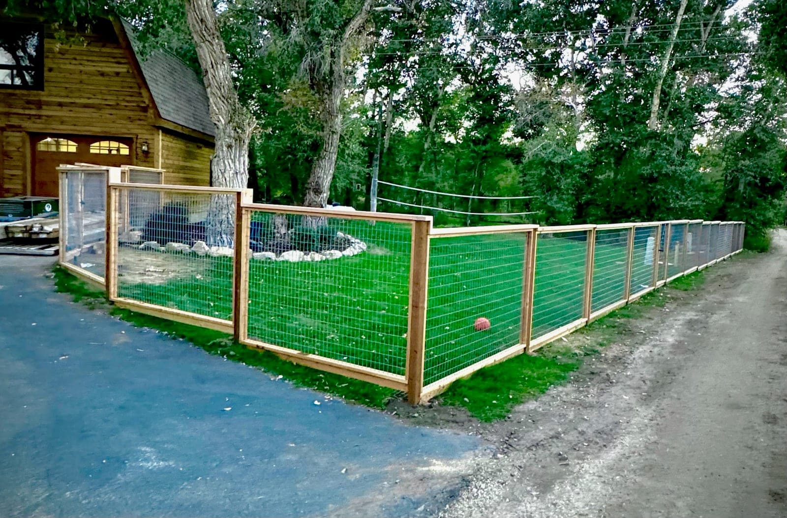 Hog wire fence panels framed in cedar around a lawn on a wooded property, Elko, Nevada