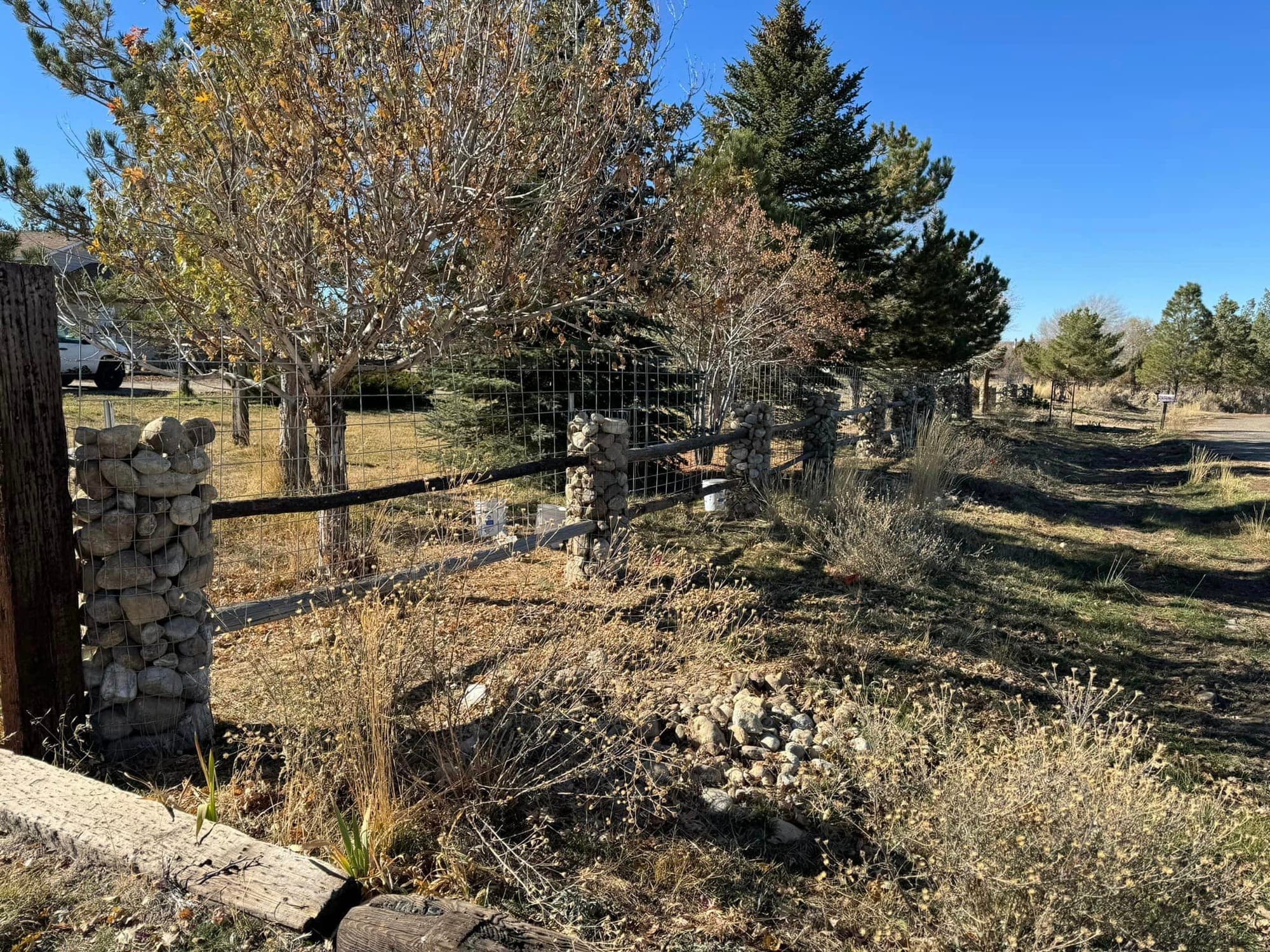 Long run of hog wire fence with rock gabion posts along a country road, Elko County, Nevada