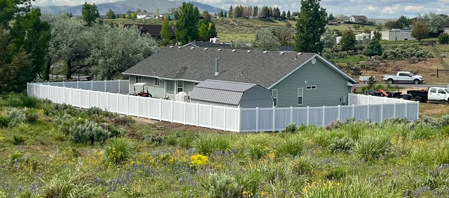 White vinyl privacy fence enclosing a backyard and shed with sagebrush hills behind, Elko, Nevada